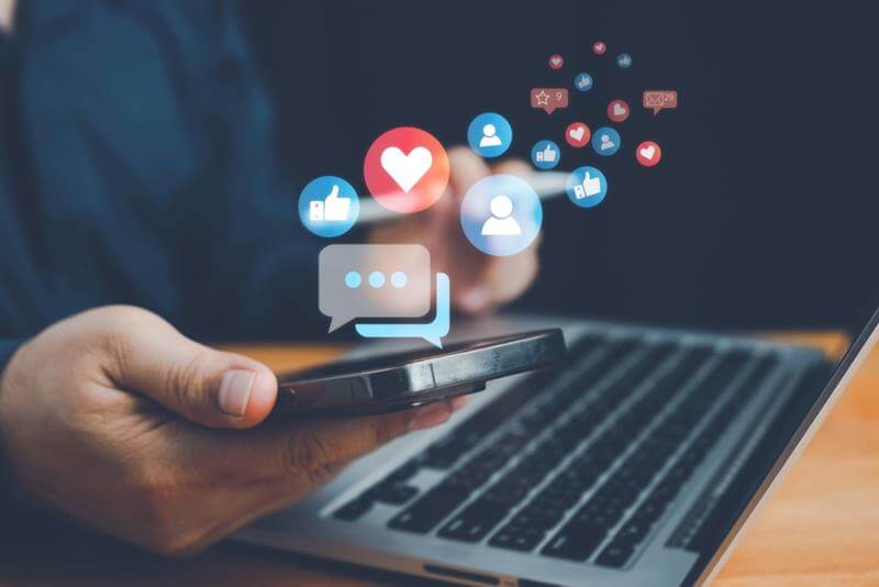 image of person checking social media n a smartphone and a laptop