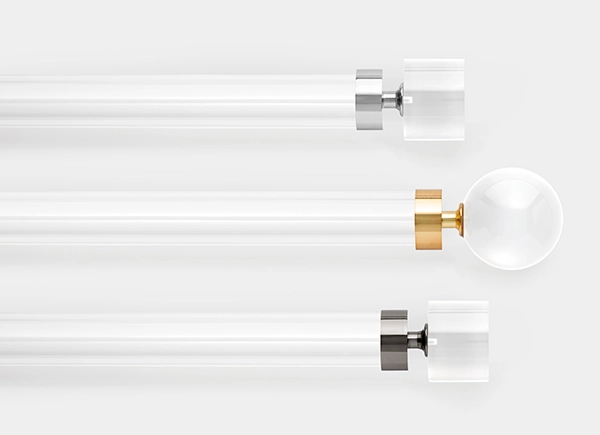 Three drapery hardware options in various Lucite finishes laid out on a white table top