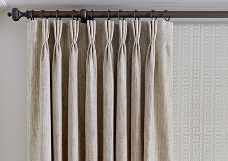 A close-up of Pinch Pleat Drapery made of Shoreline in Reed shows the three-finger pleats and rod and ring hardware