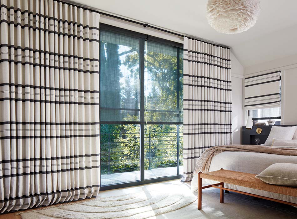 Bold Shoreham Stripe Jet Ripple Fold Drapery styled as a sliding glass door curtain in a bedroom.