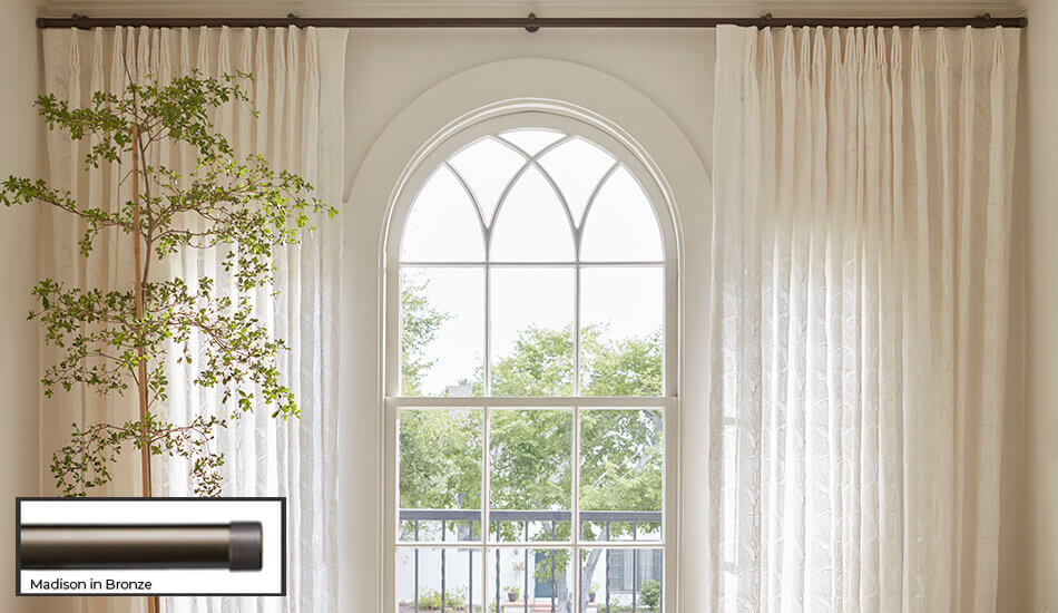 One of the window treatment trends of 2026 is seen here is having bold drapery hardware that draws the eye to the window