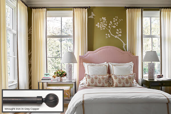 One of the window treatment trends 2026 seen in this bedroom is blending hardware in iron with ivory-colored drapery