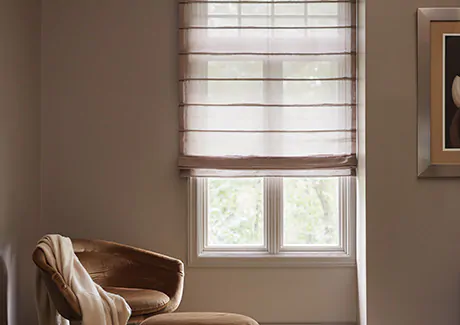 A reading nook has an Aventura Roman Shade made of Sheer Elegance in Cocoa for a delicate look that provides some privacy as decorative window coverings for soft natural light