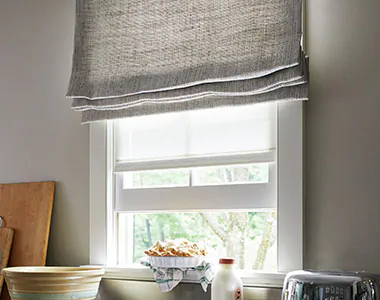 A Flat Roman Shade made of Shoreline in Pewter fabric for Roman Shades adds rustic texture to a farmhouse kitchen