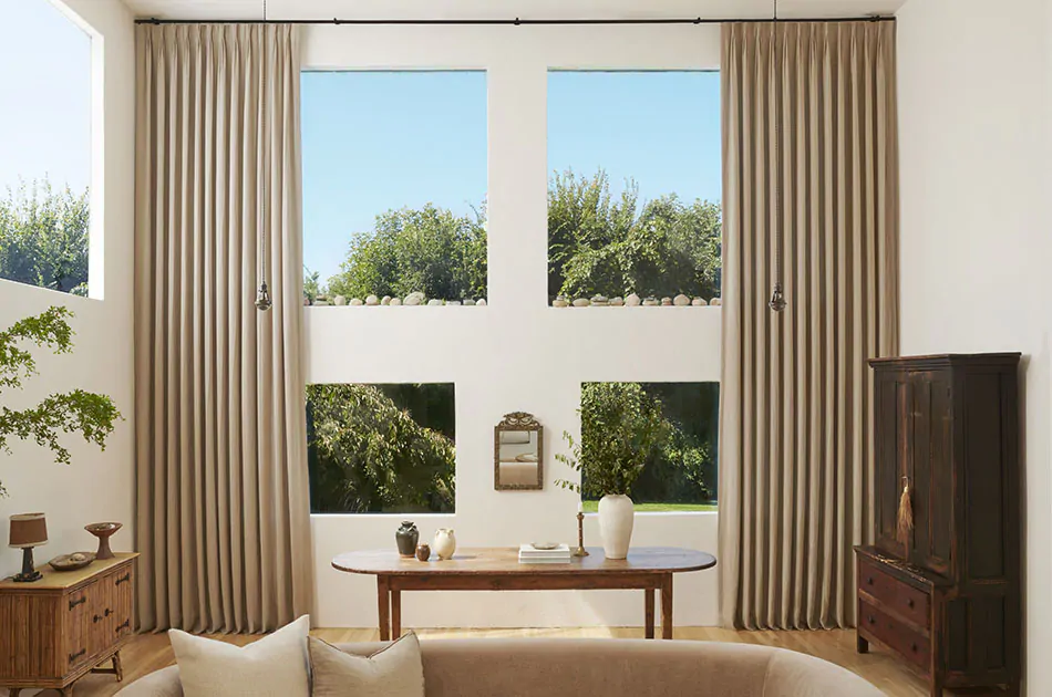 One of the window treatment trends 2026 are these floor-to-ceiling pinch pleat drapes hanging in a well-lit living room