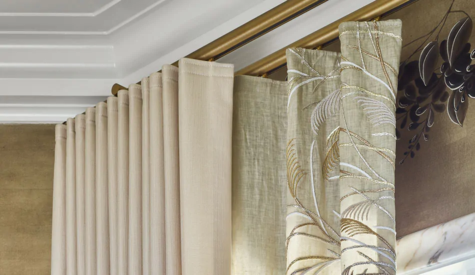 How to do double curtains: A gold double curtain rod has layered curtains of Ripple Fold Drapery in Sheer Muslin Embroidered Fabric and Neblina in Sand