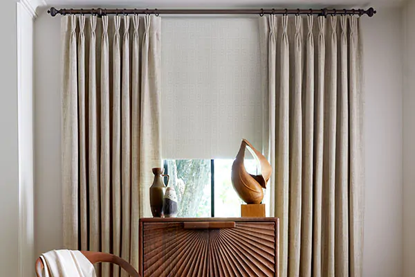 Transitional window shades of a Roller shade in Corfu and Pinch Pleat Drapery in Shoreline complement intricate furniture