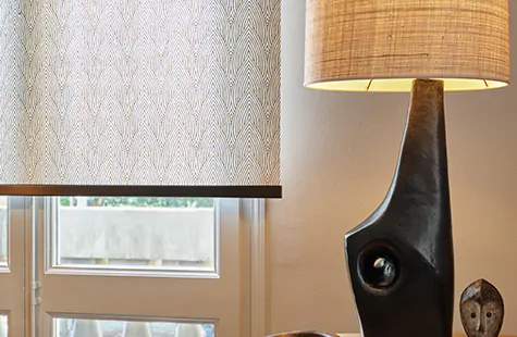 Roller Shades in a warmly decorated room feature a tea leaf pattern in brown and are used in place of blinds for a bay window