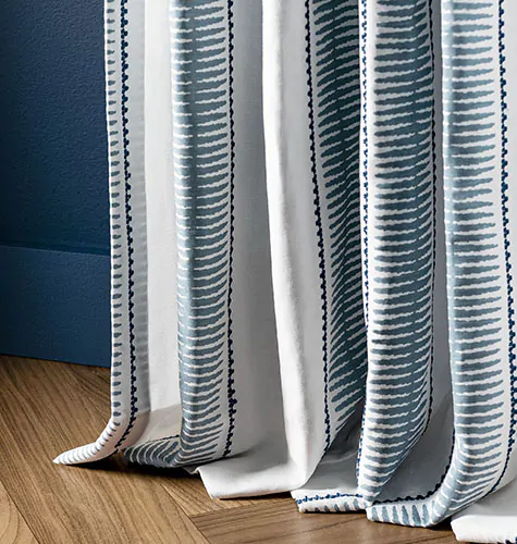 A drape panel made of Alexa Hampton's Baluster in Indigo, showing unique puddle drapes and how long curtains should be for a fuller floor-length look