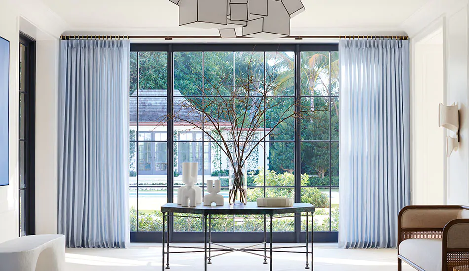 Tailored Pleat Drapery in Casa Stripe Sky in a bright modern entryway, showing break-length floor curtains that gently touch the floor