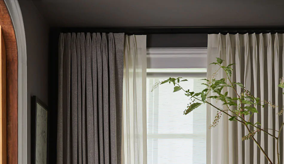 Dark gray curtains hang above a window showing how to hang curtains on a ceiling curtain track with crown molding on the window trim