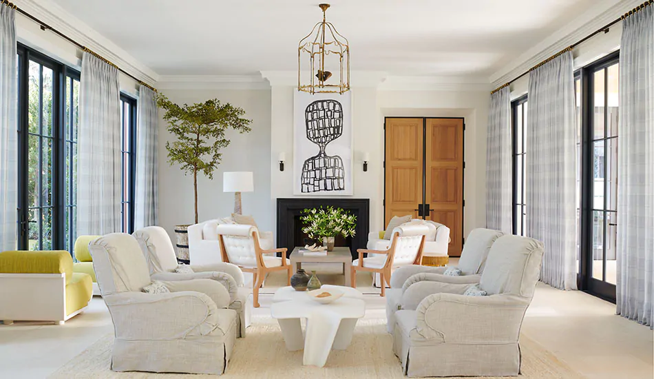 A bright transitional living room has white and black elements with warm wood tones and Tailored Pleat Drapery in Jasmine Sky