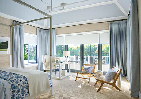 Tailored Pleat Drapery made of Vanda in Sky matches the ceiling and contrasts the beige textured wallpaper in a large bedroom as elegant window coverings with added privacy